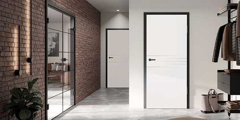 Ein moderner Flur mit zwei weißen Lasertüren mit schwarzer Zarge und Beschlägen und links einer schwarzen Loft-Glastür in einer Backsteinwand.