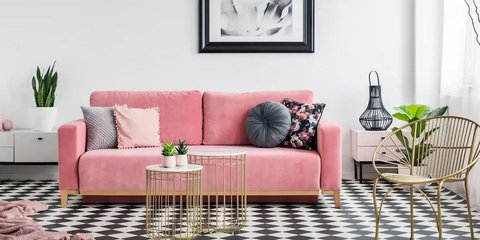 Rosa Sofa mit Kissen, goldenem Couchtisch,Karo- Boden und Pflanzen.