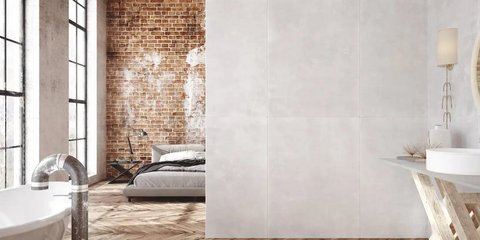 Schlafzimmer mit abgenutzter Ziegelwand,großen Fenstern, vintage Möbeln und einer freistehender Badewanne.